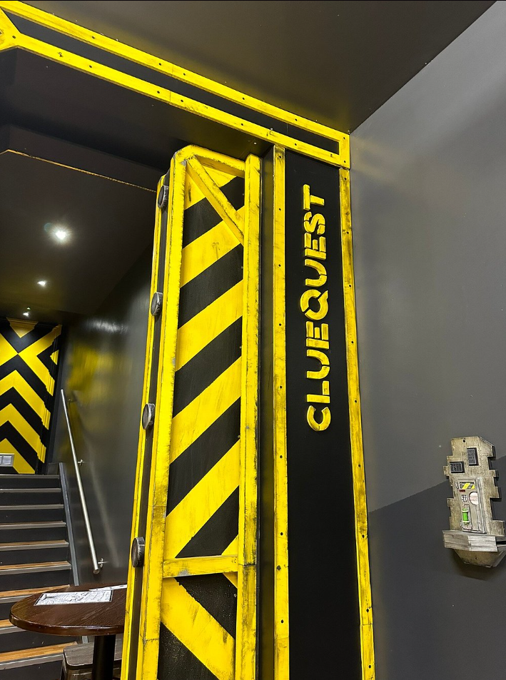 clueQuest studio entrance with the signature yellow-and-black hazard-stripe motif
